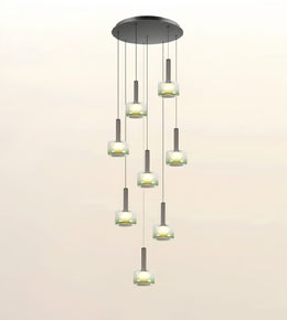 A modern multi-light chandelier pendant fixture with a circular dark metal canopy, multiple hanging cords, and cylindrical frosted glass shades glowing with warm light, shown against a plain light background.