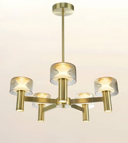 A modern five-light chandelier with a brushed gold/brass metal frame and clear glass cylindrical shades, shown against a plain off-white background.
