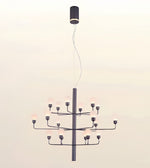 A modern multi-light chandelier with a matte black metal frame and multiple frosted glass globe bulbs, suspended from a matching black ceiling canopy against a plain off-white background.