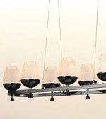 Modern linear chandelier with six textured frosted glass dome shades and black metal bowls, suspended against a plain light background.
