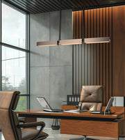 Modern office interior with a wooden desk, brown leather chairs, a long rectangular pendant light, slatted wood wall paneling, and large windows.