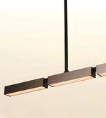 Modern linear pendant light fixture with matte black rectangular shades and warm white LED lighting, suspended by a slim black rod against a plain off-white background.