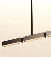 Modern linear pendant light fixture with matte black rectangular shades and warm white LED lighting, suspended by a slim black rod against a plain off-white background.