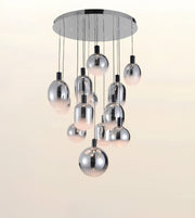 A modern multi-light chandelier with a circular chrome ceiling canopy and multiple hanging polished metal globe shades, shown against a plain light beige background.