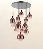 Modern chandelier with a circular chrome ceiling mount and multiple hanging rose-gold metallic glass globes against a plain light background.