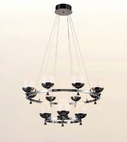 A modern multi-light chandelier with a polished silver-tone metal frame, featuring multiple frosted glass shades and dark metal cup holders, suspended from a circular ceiling canopy against a plain light background.