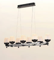 A modern 8-light linear chandelier with textured frosted glass shades and black metal accents, suspended from a rectangular ceiling mount against a plain off-white background.