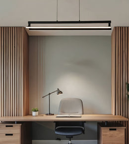 A modern black linear LED pendant light hanging above a minimalist home office desk setup with a wooden slat headboard, desk, chair, and lamp.