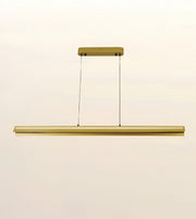 A modern linear LED pendant light fixture in a brushed gold finish, suspended by two thin black cables from a matching rectangular ceiling canopy, shown against a plain off-white background.