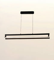 A modern linear LED pendant light fixture in black, suspended by two thin cables from a rectangular ceiling mount against a plain off-white background.