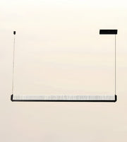 A modern linear pendant light fixture with a textured white diffuser and black metal frame, suspended by two thin cables against a plain beige background.