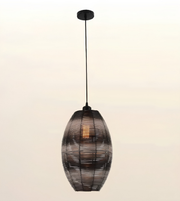 A hanging pendant light with a dark metal frame and a warm glowing bulb inside, suspended against a plain light background.