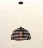 A dome-shaped pendant light with a black metal frame and a warm glowing bulb inside, suspended by a black cord from a matching black ceiling canopy against a light beige background.