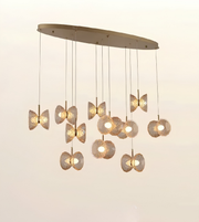 A modern oval ceiling light fixture with multiple hanging pendant lights in a butterfly or flower-like form, shown against a plain light background.