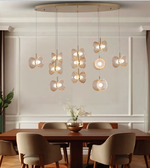 A modern multi-light pendant chandelier with butterfly-shaped glass shades hanging over a wooden dining table and chairs in a styled dining room.
