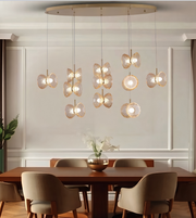 A modern multi-light pendant chandelier with butterfly-shaped glass shades hanging over a wooden dining table and chairs in a styled dining room.