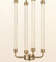 A modern three-light chandelier with clear glass cylindrical tubes and a brushed brass-finished metal base and connectors, shown against a plain off-white background.