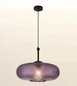 A modern pendant light with a textured, diamond-patterned purple glass shade and a matte black metal canopy and cord, shown against a plain light background.