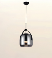 A modern pendant light with a glossy, reflective metallic dome shade suspended by a slim black cord from a round black ceiling canopy, set against a plain light beige background.