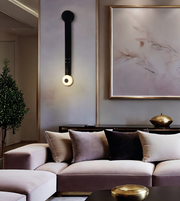 A modern living room setting featuring a plush mauve-pink sectional sofa with beige, taupe, and black velvet pillows, styled with a matching ottoman, a gold coffee table, and a large framed abstract art print on a textured gray wall.