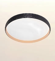 A modern flush-mount ceiling light with a textured black outer ring, a frosted white diffuser, and a warm beige inner trim, shown against a plain beige background.