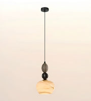 A modern pendant light fixture with a black ceiling canopy and cord, featuring stacked glass and stone-like elements including a smoky gray oval piece, a black sphere, and a warm beige marbled teardrop shade at the bottom.