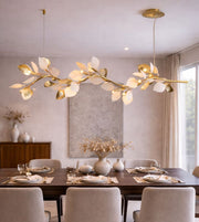 Luxury gold leaf linear pendant light suspended above a dining table with warm ambient illumination.