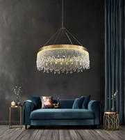 Chandelier hanging above a blue sofa in a room with dark walls and decorative elements.