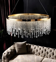 Luxury chandelier with crystal accents hanging above a sofa in a dimly lit room.