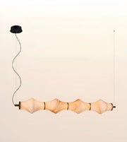 A modern multi-light linear pendant chandelier with five organic, wavy ribbed glass shades in a warm beige tone, suspended by a black cord from a black ceiling canopy against a light beige background.