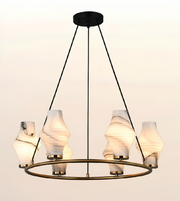 A modern six-light chandelier with a circular brass ring, black suspension rods, and textured white marble shades, shown against a plain light background.