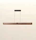 A modern linear LED pendant light with a long horizontal wooden frame in a warm brown finish, suspended by two thin cables from a rectangular black ceiling mount against a plain off-white background.