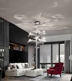 Modern living room with a chandelier, white sofa, and red armchair.