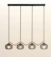 A modern 4-light linear pendant chandelier with textured gray glass shades, gold-tone metal accents, and black hanging rods against a light beige background.