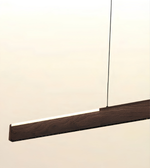A modern linear pendant light with a dark brown wood-grain finish and a thin black suspension cord, shown against a plain off-white background.