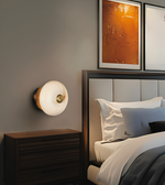 Modern circular marble-effect glass wall light with brushed brass accents, providing warm ambient illumination for contemporary interiors.