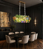 Luxury linear chandelier with handcrafted multicolour art glass discs suspended above a modern dining table.