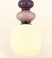 A modern pendant light fixture with a three-tiered stacked glass design. The top two tiers are in frosted dusty purple and dusty pink glass, while the large bottom tier is a warm, glowing frosted white glass shade.