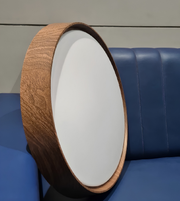Round wooden lampshade with white interior on a blue cushioned chair.