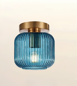 A modern semi-flush mount ceiling light fixture featuring a ribbed, translucent blue glass shade and a brushed gold metal ceiling canopy, shown against a soft beige gradient background.