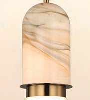 A modern pendant light with a cylindrical glass shade featuring a warm beige and cream marble pattern, accented by brushed brass metal hardware at the top and bottom.