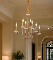 Chandelier hanging in a room with neutral walls and a window.