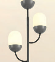 A modern three-light floor lamp with a matte black metal frame and frosted white glass shades, shown against a plain light beige background.