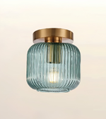 Modern fluted blue glass ceiling light with brushed brass finish and decorative filament bulb.