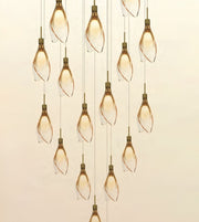 A modern multi-light linear chandelier with multiple clear glass pendant bulbs wrapped in a twisted spiral, suspended by thin cords against a warm beige background.