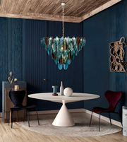 Modern dining room with a blue glass chandelier, round white table, and dark blue walls.