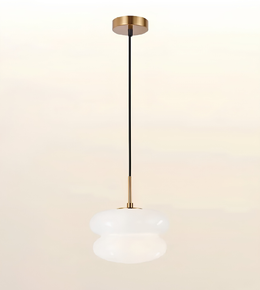 A modern pendant light fixture with a brushed gold ceiling canopy and downrod, a black cord, and a frosted white glass shade, shown against a soft beige gradient background.