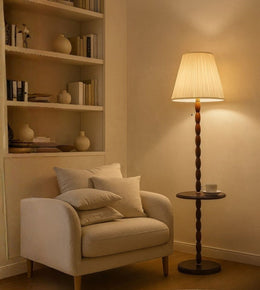 Wooden floor lamp with fabric shade beside armchair in cozy living room