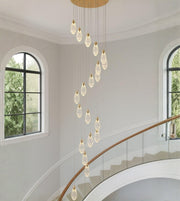 Crystal drop cascade staircase chandelier with modern teardrop pendants in a double height interior