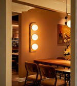 Dining room with wooden table and chairs, wall-mounted light fixture, and framed picture on the wall.